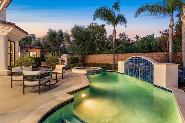 pool at dusk with an in ground hot tub