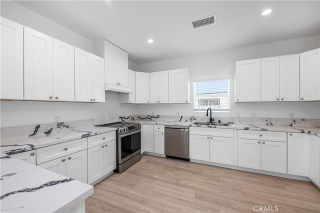 kitchen featuring light stone countertops, appliances with stainless steel finishes, light wood-type flooring, sink, and white cabinets