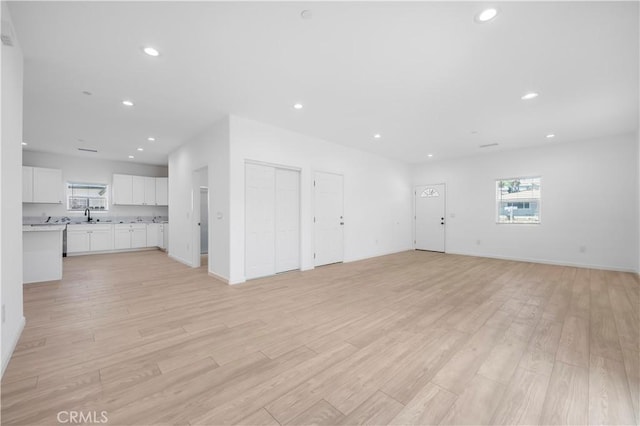 unfurnished living room featuring light wood-type flooring and sink