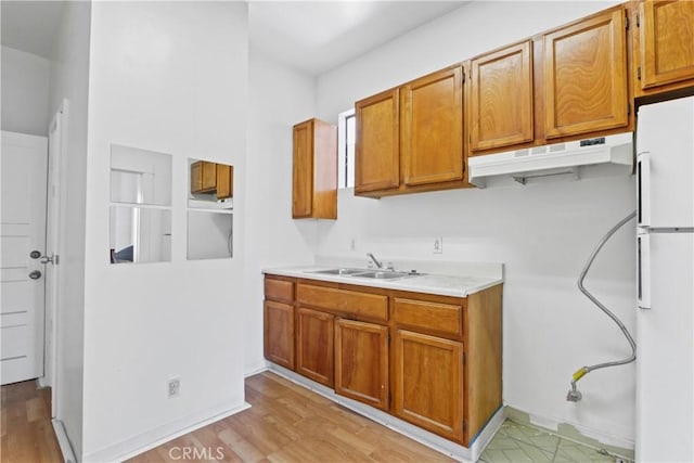 kitchen featuring sink, light wood-type flooring, and white refrigerator