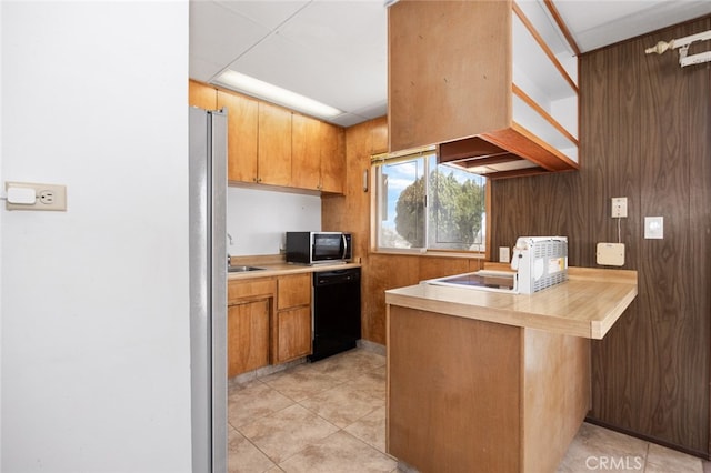 kitchen featuring appliances with stainless steel finishes, wooden walls, sink, and light tile patterned floors