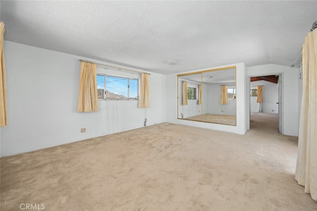 carpeted spare room with vaulted ceiling and a textured ceiling