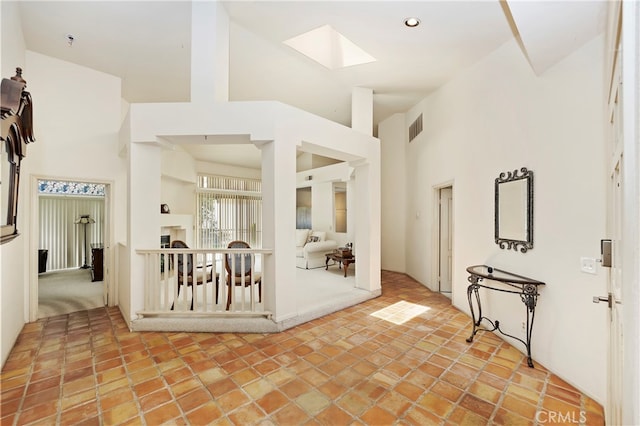 foyer featuring a towering ceiling and a skylight