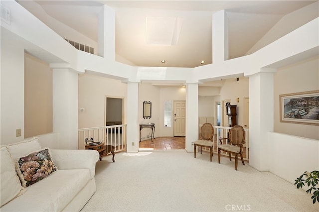 living room with decorative columns, light carpet, and high vaulted ceiling