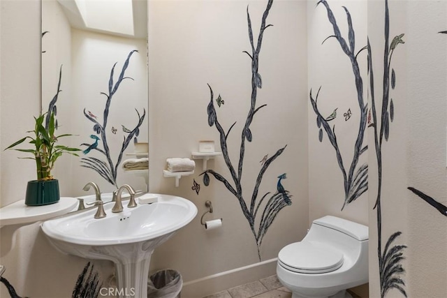 bathroom with tile patterned floors, toilet, and a skylight