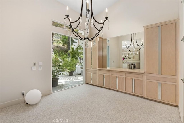 spare room with high vaulted ceiling, light colored carpet, and an inviting chandelier