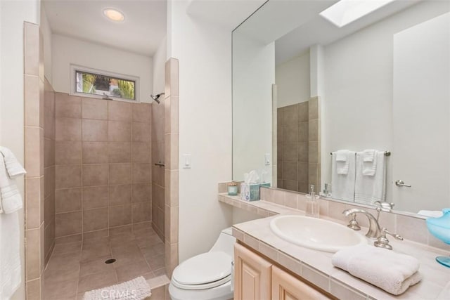 bathroom featuring tile patterned flooring, vanity, tiled shower, and toilet