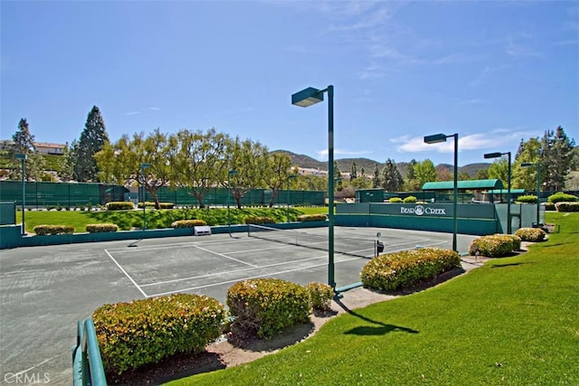 view of sport court featuring a mountain view and a yard