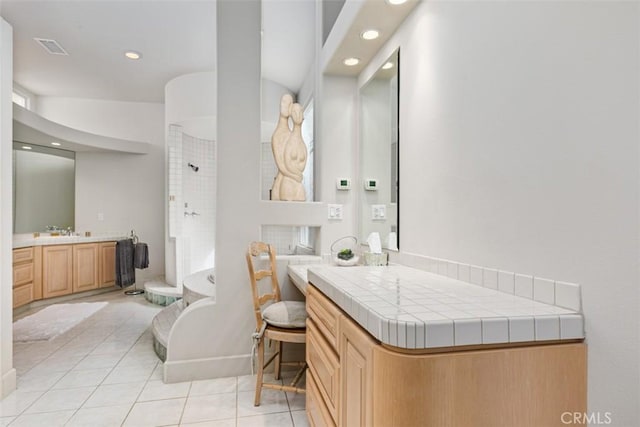 bathroom featuring a tile shower, tile patterned flooring, and vanity