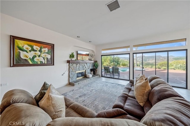 living room with concrete flooring, a mountain view, and a stone fireplace