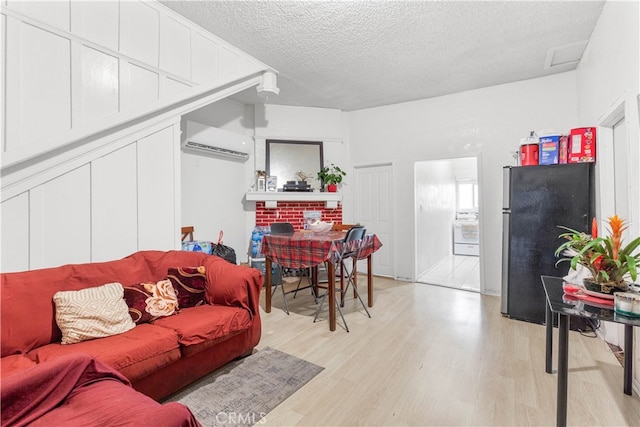 living room with light hardwood / wood-style flooring, a wall unit AC, a fireplace, and a textured ceiling