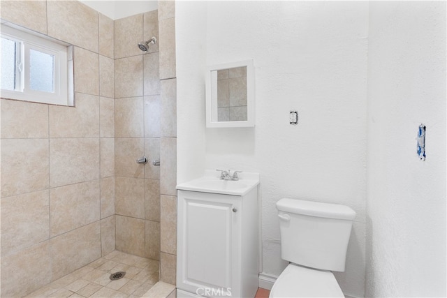 bathroom featuring tiled shower, vanity, and toilet