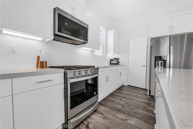 kitchen featuring light stone countertops, appliances with stainless steel finishes, dark hardwood / wood-style flooring, tasteful backsplash, and white cabinets