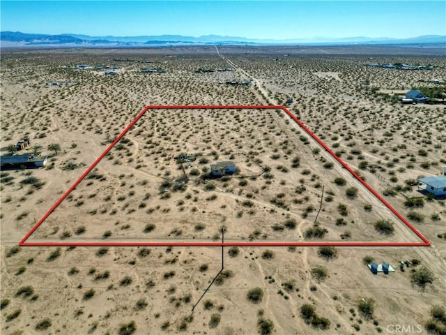 drone / aerial view featuring a mountain view and a desert view