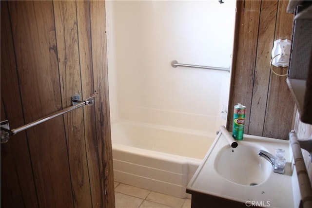 full bath with wood walls, a sink, and tile patterned floors