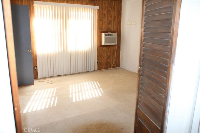 empty room with a wall unit AC, light colored carpet, and wooden walls