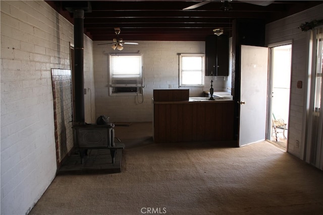 kitchen featuring light colored carpet, ceiling fan, and a wood stove