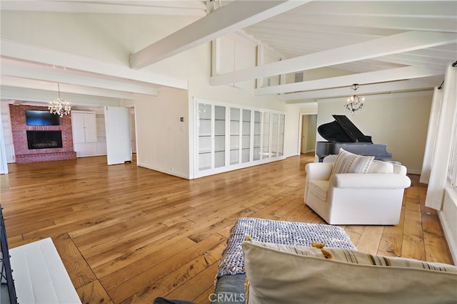 living room with hardwood / wood-style floors, beam ceiling, an inviting chandelier, high vaulted ceiling, and a fireplace