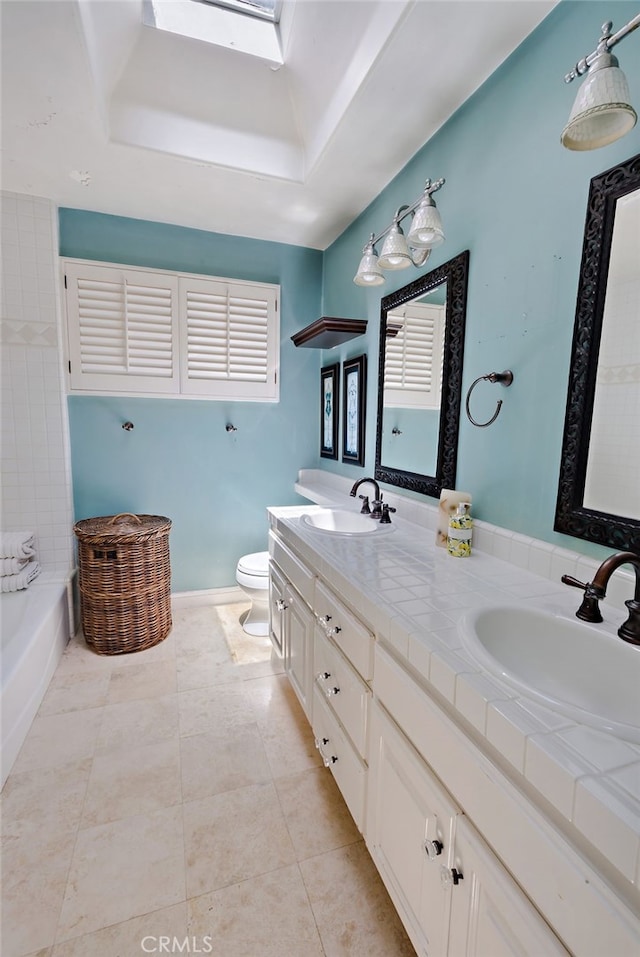 bathroom with a skylight, a tub, a tray ceiling, toilet, and vanity