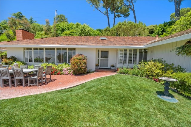 back of house featuring a patio area and a lawn