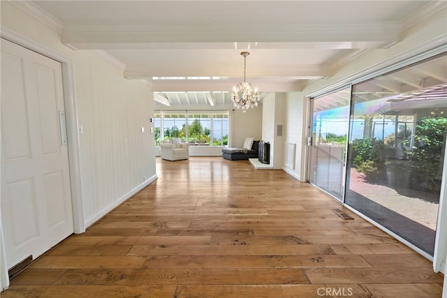 corridor with a notable chandelier, hardwood / wood-style flooring, ornamental molding, and beam ceiling