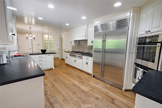 8 Quail Ridge Rd S, Rolling Hills, CA 90274 - kitchen with stainless steel appliances, a sink, premium range hood, white cabinetry, and a chandelier