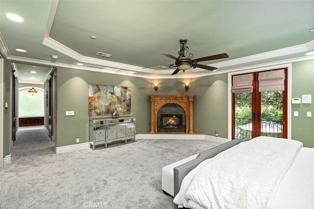 bedroom featuring multiple windows, a raised ceiling, ornamental molding, and access to exterior