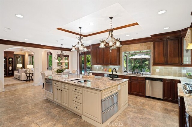 kitchen with light stone counters, a notable chandelier, backsplash, and stainless steel dishwasher