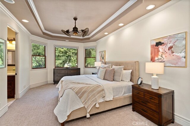 carpeted bedroom with ceiling fan, a tray ceiling, connected bathroom, and ornamental molding