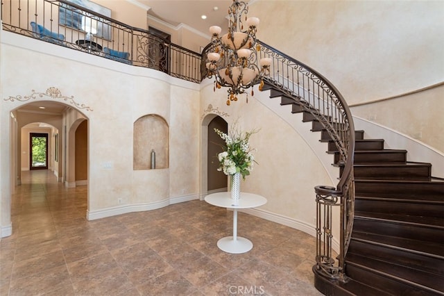 staircase featuring ornamental molding, a high ceiling, and a chandelier