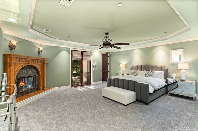 carpeted bedroom featuring a tray ceiling, ceiling fan, and multiple windows