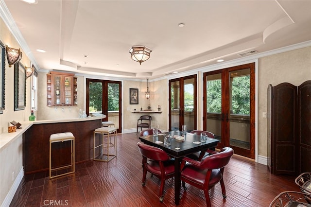 dining area featuring a raised ceiling, bar area, dark hardwood / wood-style flooring, and french doors