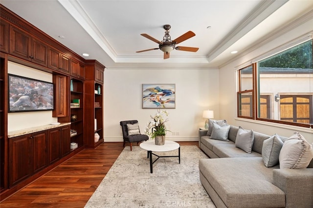 living room featuring a tray ceiling, ceiling fan, crown molding, and dark hardwood / wood-style flooring