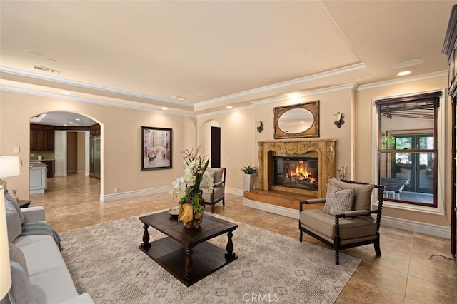 living room with ornamental molding, a premium fireplace, and a raised ceiling