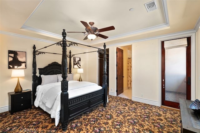 bedroom featuring ceiling fan, carpet floors, a tray ceiling, and ensuite bath