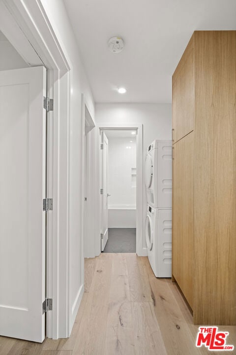 hall with light hardwood / wood-style floors and stacked washer and clothes dryer