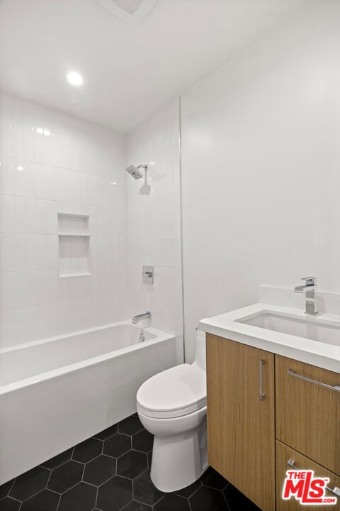 full bathroom featuring vanity, toilet, tiled shower / bath combo, and tile patterned flooring