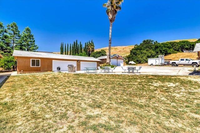 view of front of property featuring a front yard, a patio, an outdoor structure, and a garage