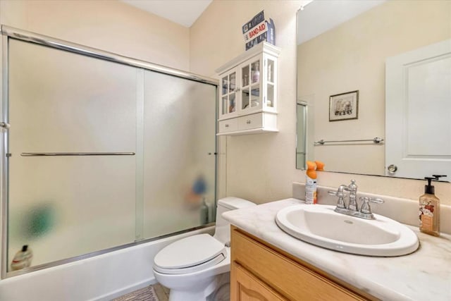 full bathroom featuring toilet, bath / shower combo with glass door, and vanity