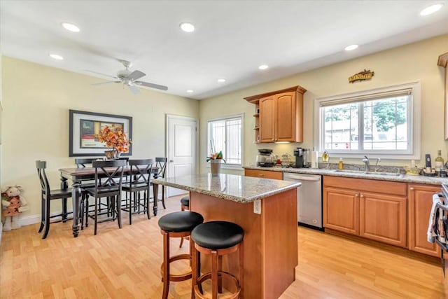 kitchen featuring a kitchen island, light hardwood / wood-style floors, stainless steel dishwasher, and sink