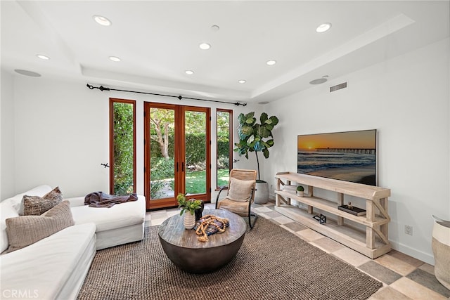 living area with visible vents, a raised ceiling, baseboards, french doors, and recessed lighting