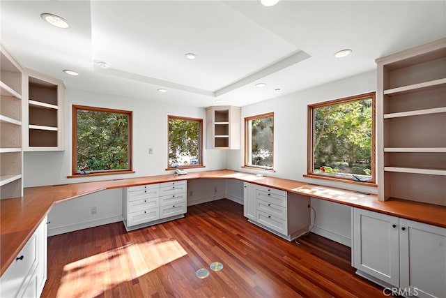 unfurnished office featuring recessed lighting, a raised ceiling, built in study area, and dark wood finished floors