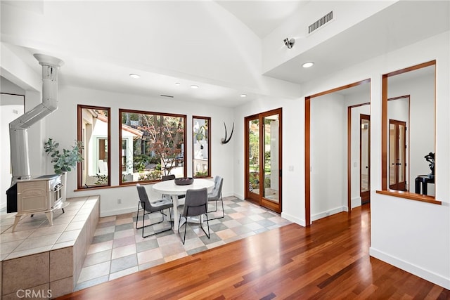 dining space featuring baseboards, visible vents, wood finished floors, a wood stove, and recessed lighting