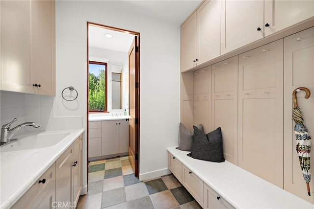 mudroom featuring light floors and a sink