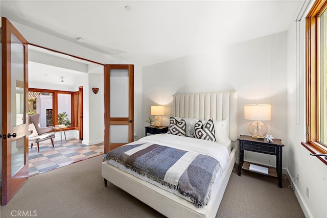 carpeted bedroom featuring tile patterned floors, multiple windows, and baseboards