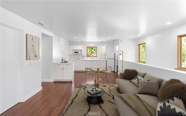 living area with dark wood-style floors, baseboards, visible vents, and recessed lighting