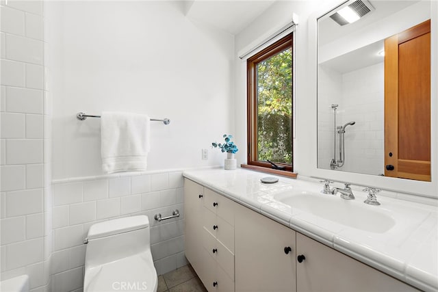 full bath with tile walls, visible vents, toilet, wainscoting, and a tile shower