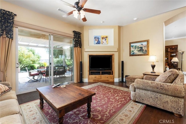 living area with visible vents, a ceiling fan, ornamental molding, wood finished floors, and baseboards