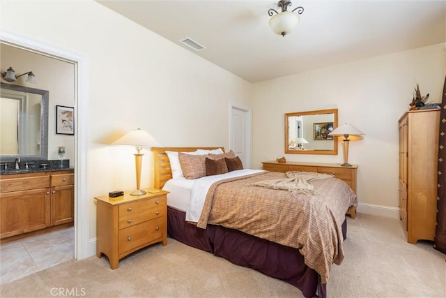 bedroom with light colored carpet, visible vents, a sink, and ensuite bath