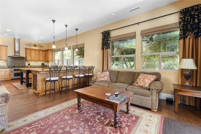 living room with baseboards, plenty of natural light, visible vents, and light wood-style floors